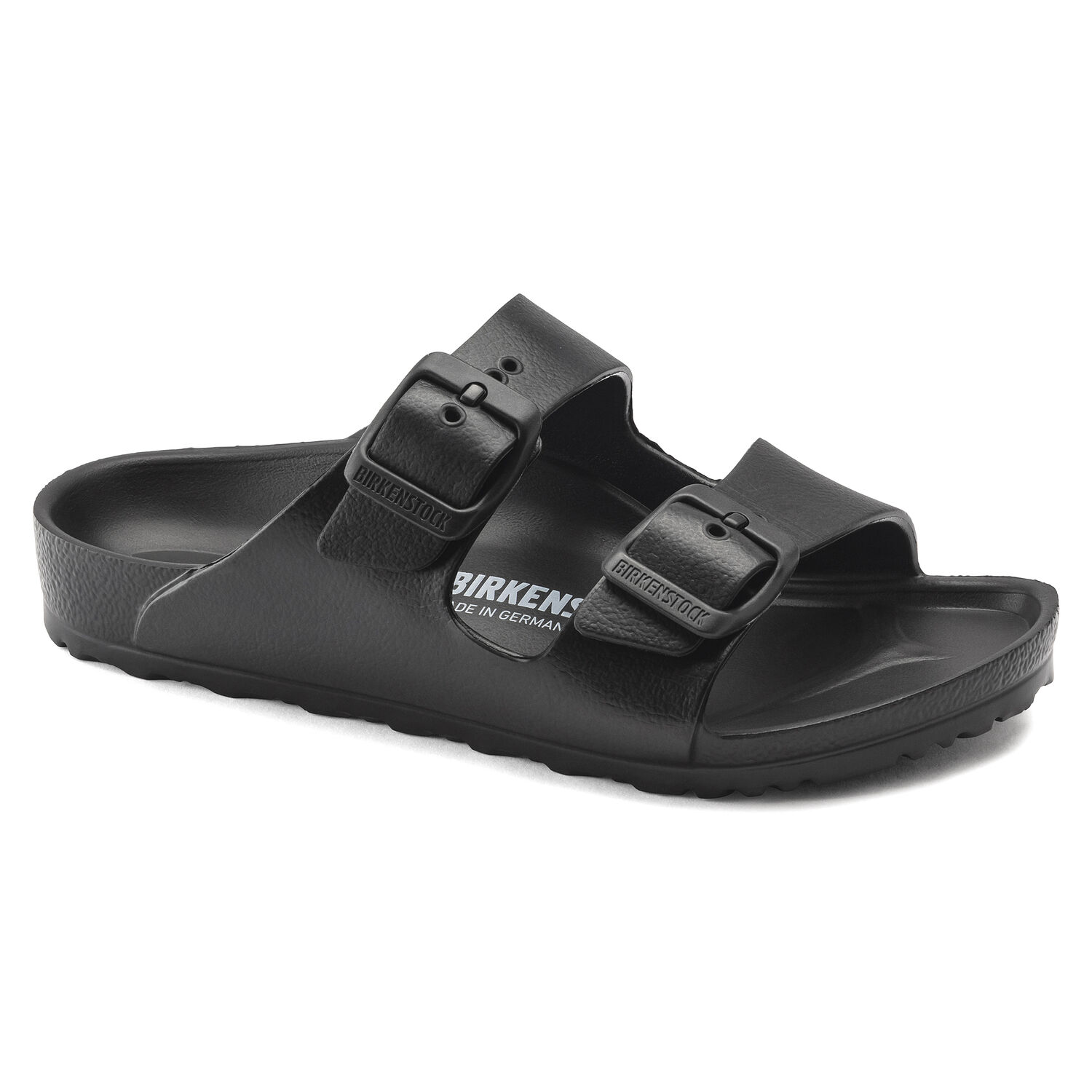 Une paire de sandales Birkenstock Arizona Kids noires avec deux boucles sur un fond blanc. Les sandales ont une assise anatomique en liège et une semelle extérieure en EVA souple. Les sangles sont fabriquées en cuir synthétique Birko-Flor, qui est doux et résistant à l'eau.