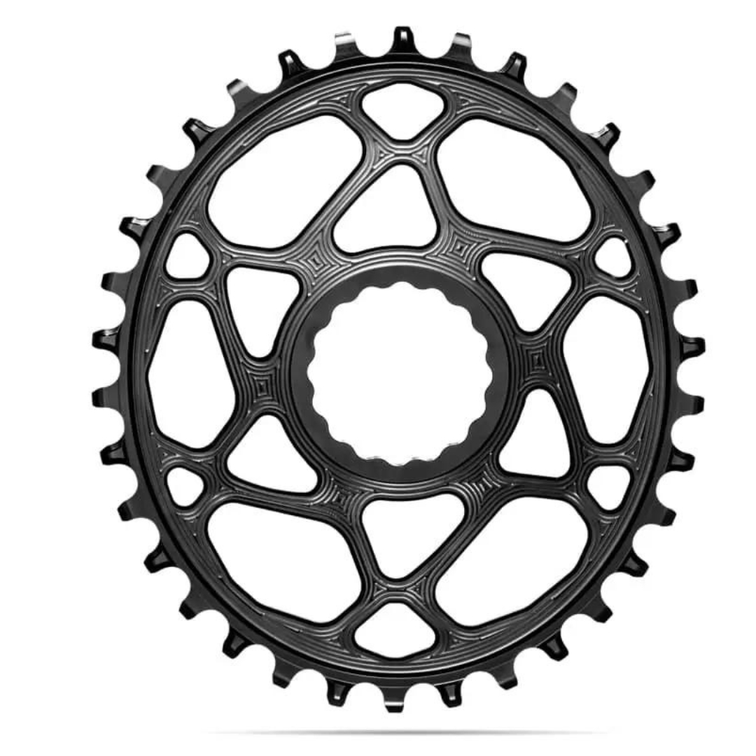 Un plateau de vélo noir avec une structure en forme de toile d'araignée au design complexe et des dents régulièrement espacées le long du bord extérieur. Le plateau est doté d'un trou central circulaire pour le montage sur le pédalier du vélo. L'apparence générale est élégante et moderne.