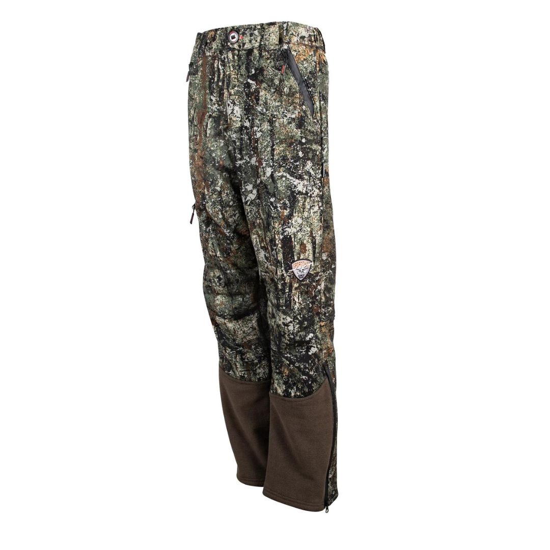 Pantalon de chasse camouflage avec empiècements marron aux genoux et aux jambes. Le pantalon possède une poche zippée sur le côté et une fermeture à bouton à la taille. Le motif camouflage présente des couleurs vertes, marron et beiges.