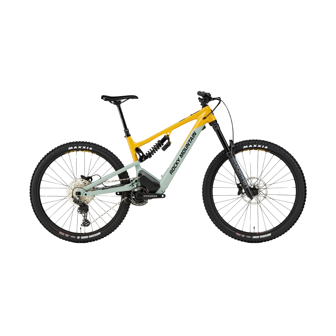 Un VTT robuste avec un cadre jaune et vert, une suspension intégrale et de gros pneus à crampons. Il est équipé de freins à disque et d'une fourche avant robuste, conçue pour le cyclisme tout-terrain. Le nom de la marque est visible sur le cadre.