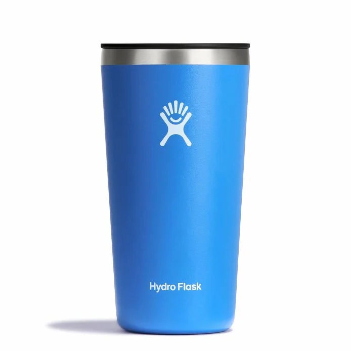 Un gobelet Hydro Flask bleu avec un bord en acier inoxydable, sur lequel sont imprimés le logo et le nom de la marque Hydro Flask. Le gobelet est placé à la verticale sur un fond blanc.