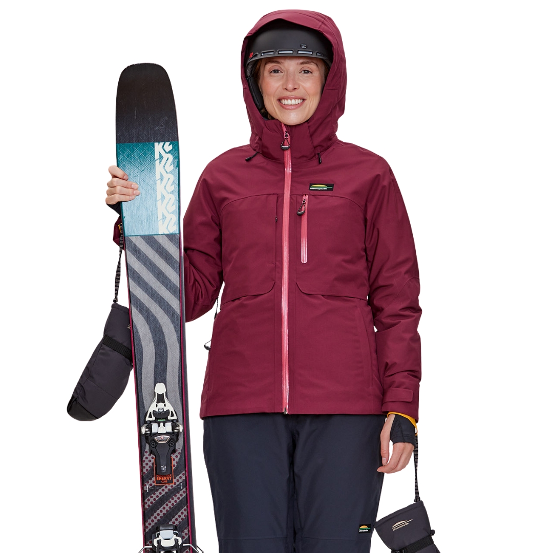 MANTEAU DE SKI ALPIN CHLOROPHYLLE EIRA POUR FEMME couleur CERISE FONCÉE vu du manteau rose fuschia très foncé porté par une femme vue de la tête aux cuisses de face avec un équipememnt de ski