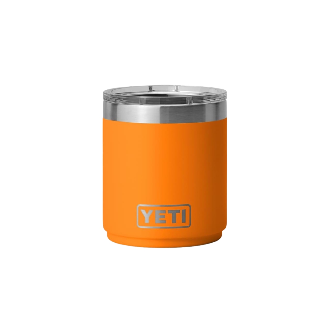 Un gobelet isotherme YETI orange vif, doté d'un couvercle argenté et d'un bord en acier inoxydable. Le gobelet cylindrique porte le logo YETI bien en évidence près du fond. Sur fond blanc uni.